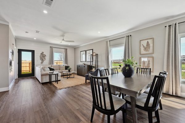 Great room living area at Verse Lockhart with large kitchen table and sofa sectional in view with modern accents and rugs.